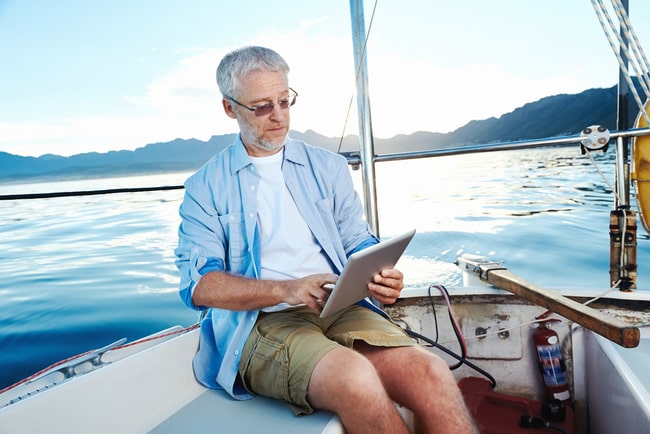 Man på segelbåt letar efter ljudböcker på sin Ipad